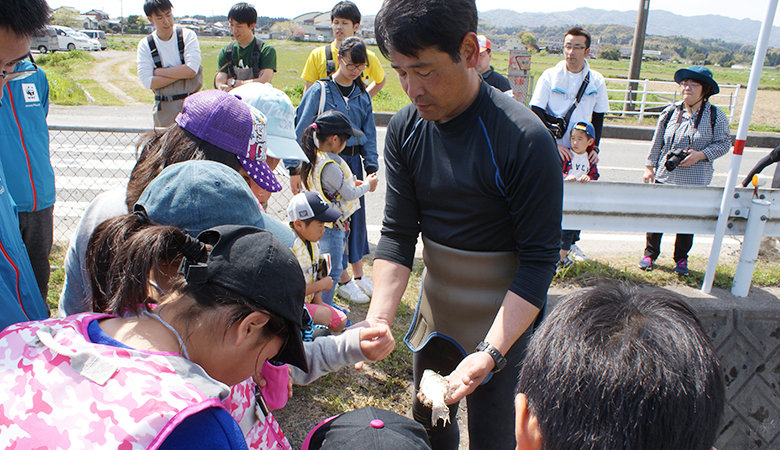 投網で捕れた淡水魚を手に持ち、子どもたちに説明する鬼倉先生。この後魚は水路に戻しました。