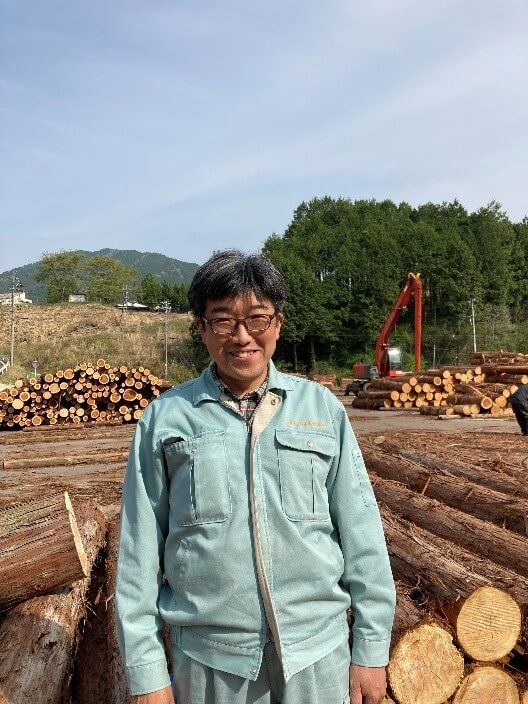 木材市場を案内してくださった森林組合の大崎業務課長。東白川村の木材市場には東濃ひのきやスギの丸太がずらりと並びます。