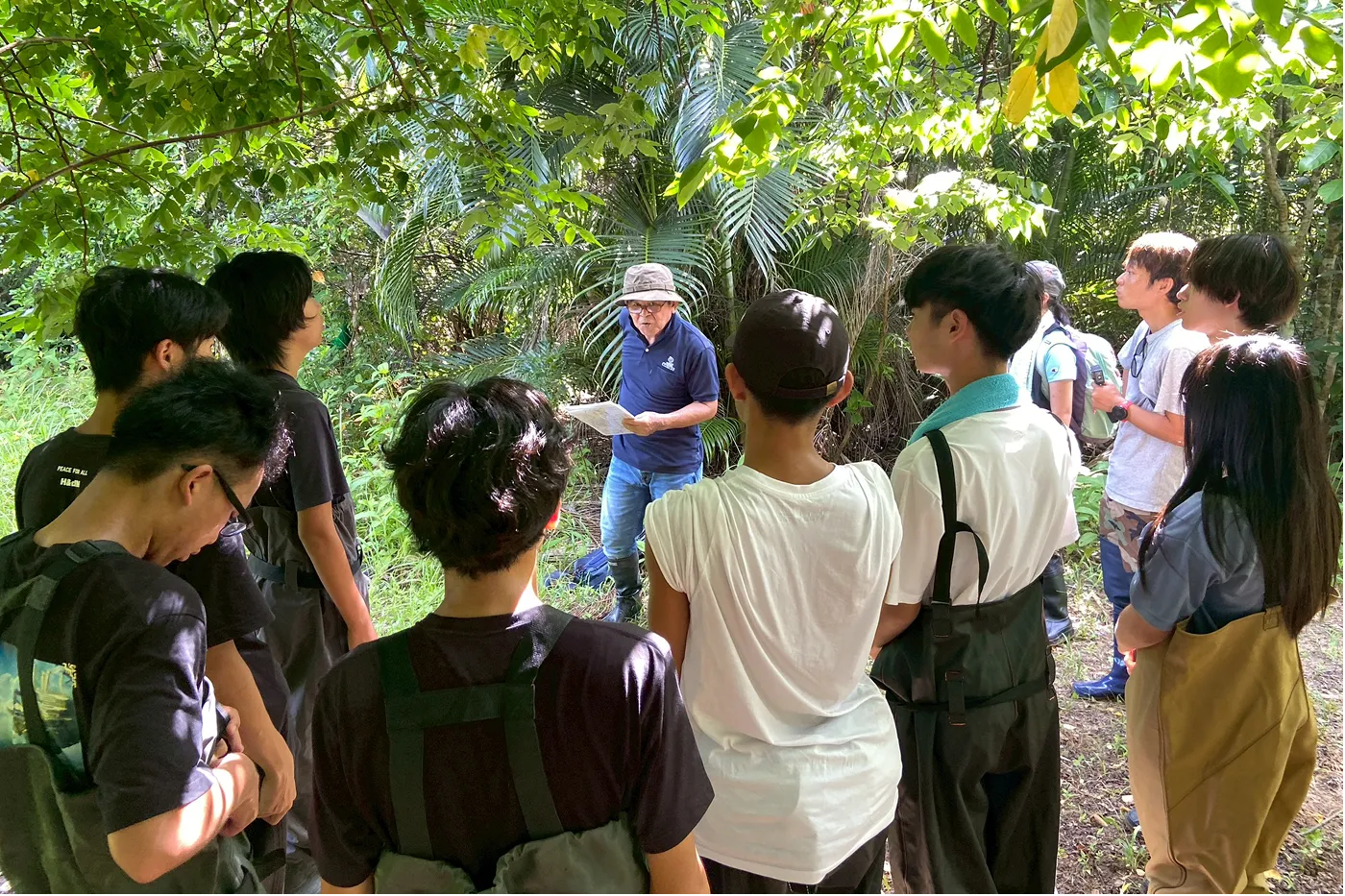 船で稲葉へ上陸後、元稲葉住民の平良彰健さん（浦内川観光）からお話を聞く参加者達