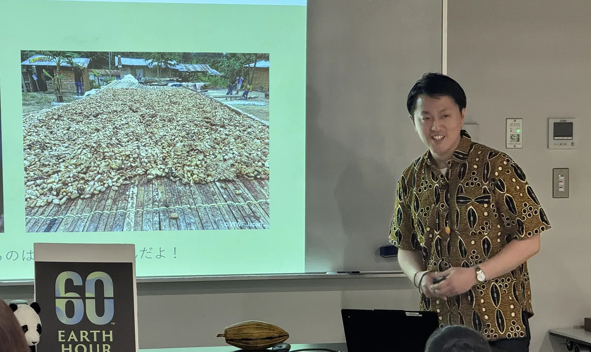 日本が輸入するカカオ豆の7割以上はガーナ産。そのガーナを訪れた際に購入してきたシャツと、カカオの実をモチーフにしたネックレスを身に付けて登壇。