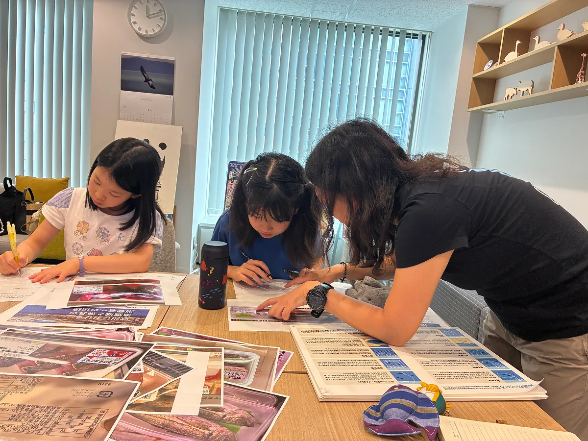 WWFのスタッフと、さまざまな製品のラベルを調べる子ども記者。WWFジャパンが作成した『おさかなハンドブック』も活用しながら、魚の履歴書づくりに挑戦しました。
